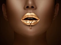 Golden lipstick closeup. Liquid metal dripping from gold lips. Beautiful makeup. Sexy lips, bright liquid paint on girl`s mouth
