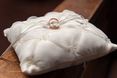 Golden wedding rings on white satin pillow on wooden hand rail stock images Golden wedding rings on white satin pillow on wooden hand rail stock images