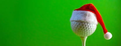 The golf ball mounted on the tee is wearing a Santa Claus souvenir hat. Blank for a postcard for a golfer to celebrate the New stock photography The golf ball mounted on the tee is wearing a Santa Claus souvenir hat. Blank for a postcard for a golfer to celebrate the New stock photography