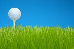 Golf ball on tee in a grass field