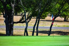 Golf Green in Central Texas lined with Trees with a lonestar Texas flag as golf flag stock image Golf Green in Central Texas lined with Trees with a lonestar Texas flag as golf flag stock image