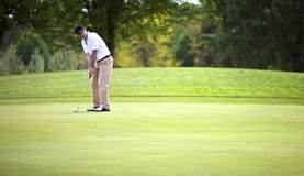 Golf player putting on green