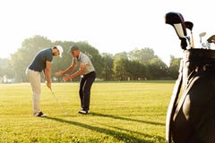 Golfe praticando do desportista novo com seu professor foto de stock Golfe praticando do desportista novo com seu professor foto de stock