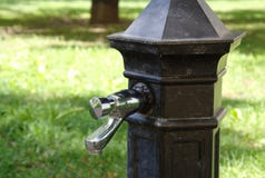 Golpecito de suministro de agua tradicional con agua potable en el parque imagenes de archivo Golpecito de suministro de agua tradicional con agua potable en el parque imagenes de archivo