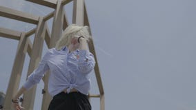 Gorgeous passionate teen blonde woman shaking hips dancing latino style outside with summer sky and building in background - stock video footage Gorgeous passionate teen blonde woman shaking hips dancing latino style outside with summer sky and building in background - stock video footage