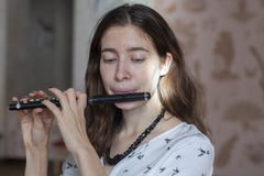 A gorgeous young woman sitting and playing the flute piccolo stock photo A gorgeous young woman sitting and playing the flute piccolo stock photo