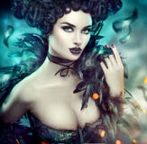 Gothic sexy young woman. Halloween. Beautiful model girl with fantasy makeup in goth costume with black feathers