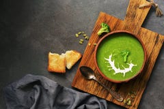 Gr?ne Sahnebrokkolisuppe mit Sahne und K?rbiskernen in einer keramischen Sch?ssel auf einem Schneidebrett, dunkler rustikaler Hin stockfotos Gr?ne Sahnebrokkolisuppe mit Sahne und K?rbiskernen in einer keramischen Sch?ssel auf einem Schneidebrett, dunkler rustikaler Hin stockfotos