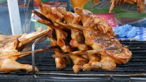 Grade da carcaça da galinha inteira amarrada no churrasco de madeira da vara na grade Alimento Tailândia da rua As mãos do ` s do video estoque Grade da carcaça da galinha inteira amarrada no churrasco de madeira da vara na grade Alimento Tailândia da rua As mãos do ` s do video estoque