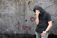 Grafittis do amo do si e menino infeliz com hoodie preto imagens de stock Grafittis do amo do si e menino infeliz com hoodie preto imagens de stock