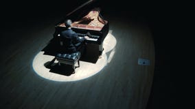 Grand Piano On Stage : An elegant man in a black suit playing grand piano on stage in a concert hall, aerial video