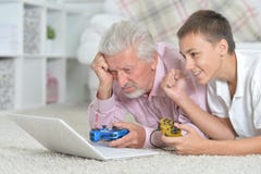 Grand-père et petit-fils jouant des jeux d'ordinateur Photos stock Grand-père et petit-fils jouant des jeux d'ordinateur Photos stock
