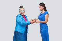 Granddaughter gives a gift to a funny old grandmother stock photos Granddaughter gives a gift to a funny old grandmother stock photos