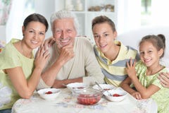 Grande famille heureuse mangeant les fraises fraîches à la cuisine Photos libres de droits Grande famille heureuse mangeant les fraises fraîches à la cuisine Photos libres de droits