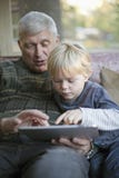 Grandfather and grandson using Tablet PC. Grandson using touchscreen tablet PC with grandfather Grandfather and grandson using Tablet PC. Grandson using touchscreen tablet PC with grandfather