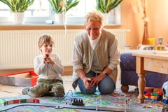 Grandmother and little grandson playing with racing cars Royalty Free Stock Images Grandmother and little grandson playing with racing cars Royalty Free Stock Images