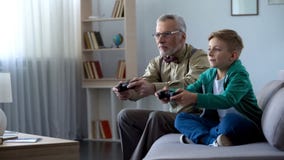 Grandpa и внук играя видеоигру с консолью, счастливое время совместно стоковая фотография rf Grandpa и внук играя видеоигру с консолью, счастливое время совместно стоковая фотография rf