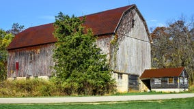 Grange rustique de Brown parmi des arbres photos stock Grange rustique de Brown parmi des arbres photos stock