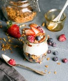 Granola d'avoine de yaourt avec les baies fraîches, les écrous, le miel et les feuilles en bon état dans le pot en verre sur le c photo stock Granola d'avoine de yaourt avec les baies fraîches, les écrous, le miel et les feuilles en bon état dans le pot en verre sur le c photo stock
