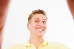 Grappige gekke mens die in toevallige t-shirt op camera met duim glimlachen omhoog terwijl nemen selfie geïsoleerd over witte ach royalty-vrije stock foto Grappige gekke mens die in toevallige t-shirt op camera met duim glimlachen omhoog terwijl nemen selfie geïsoleerd over witte ach royalty-vrije stock foto