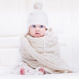 Grappige leuke baby die hoed en reusachtige gebreide sjaal dragen stock foto Grappige leuke baby die hoed en reusachtige gebreide sjaal dragen stock foto