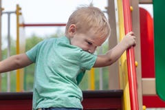 Grappige leuke Kaukasische de jongensspelen van de blondebaby op de speelplaats, die aan upstair beklimmen royalty-vrije stock afbeeldingen Grappige leuke Kaukasische de jongensspelen van de blondebaby op de speelplaats, die aan upstair beklimmen royalty-vrije stock afbeeldingen