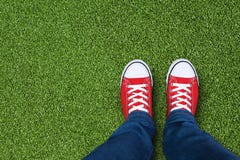 Grasgebied met voeten die rode tennisschoenen dragen royalty-vrije stock fotografie Grasgebied met voeten die rode tennisschoenen dragen royalty-vrije stock fotografie