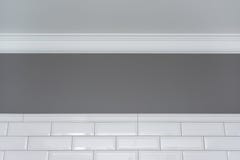Grau malte Wand, weißes Deckenformteil und kleinen weißen glatten Ziegelstein der keramischen dekorativen Fliesen Fragment der Wä lizenzfreie stockbilder Grau malte Wand, weißes Deckenformteil und kleinen weißen glatten Ziegelstein der keramischen dekorativen Fliesen Fragment der Wä lizenzfreie stockbilder