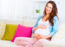 Gravid kvinnasammanträde på en soffa arkivbilder Gravid kvinnasammanträde på en soffa arkivbilder