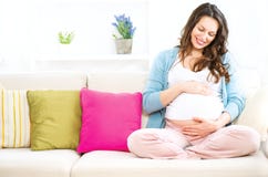 Gravid kvinnasammanträde på en soffa fotografering för bildbyråer Gravid kvinnasammanträde på en soffa fotografering för bildbyråer