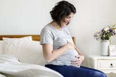 Gravid kvinnasammanträde på sängen royaltyfria foton Gravid kvinnasammanträde på sängen royaltyfria foton