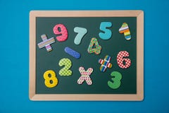 Green chalkboard with wooden frame, colorful math operation signs and numbers, blue background stock image Green chalkboard with wooden frame, colorful math operation signs and numbers, blue background stock image