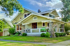 Green old craftsman style home with covered porch.