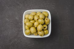 Green Olives In A White Ceramic Bowl On A Dark Concrete Background. Top View. Close-up Royalty Free Stock Image