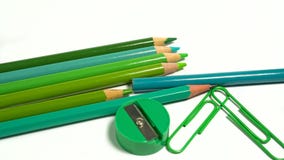 Green tones paper clips, colored pencils and pencil sharpener on white background Stock Photo Green tones paper clips, colored pencils and pencil sharpener on white background Stock Photo