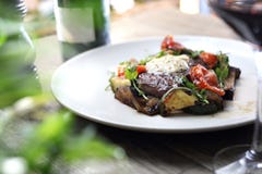 Grillad biff av entrecôte med örtsmör och grillade grönsaker tjänade som på en vit platta arkivfoto Grillad biff av entrecôte med örtsmör och grillade grönsaker tjänade som på en vit platta arkivfoto