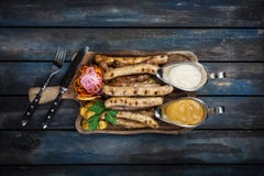 Grillade korvar med surkål- och potatiskilar arkivbild Grillade korvar med surkål- och potatiskilar arkivbild