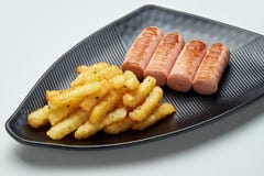 Grilled fries and sausages on a black plate royalty free stock photography Grilled fries and sausages on a black plate royalty free stock photography