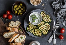 Grilled zucchini, olives, tomatoes, ciabatta - simple snack or appetizer. Mediterranean style food. On a dark background, top view royalty free stock photography Grilled zucchini, olives, tomatoes, ciabatta - simple snack or appetizer. Mediterranean style food. On a dark background, top view royalty free stock photography