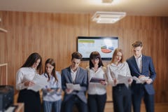 Gro?es Team von Leuten arbeitet bei einem Tisch f?r Laptops, Tabletten und Papiere, auf dem Hintergrund ein gro?er Fernseher auf stockbild Gro?es Team von Leuten arbeitet bei einem Tisch f?r Laptops, Tabletten und Papiere, auf dem Hintergrund ein gro?er Fernseher auf stockbild