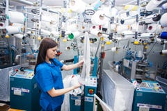 GRODNO, BIELORUSSIA - 13 DICEMBRE 2013: Cucitrice nella fabbrica del tessuto che cuce con una macchina da cucire industriale Fotografia Stock Libera da Diritti GRODNO, BIELORUSSIA - 13 DICEMBRE 2013: Cucitrice nella fabbrica del tessuto che cuce con una macchina da cucire industriale Fotografia Stock Libera da Diritti