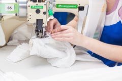 GRODNO, BIELORUSSIA - 13 DICEMBRE 2013: Cucitrice nella fabbrica del tessuto che cuce con una macchina da cucire industriale Immagini Stock Libere da Diritti GRODNO, BIELORUSSIA - 13 DICEMBRE 2013: Cucitrice nella fabbrica del tessuto che cuce con una macchina da cucire industriale Immagini Stock Libere da Diritti
