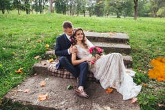 Groom bride with a bouquet hugging and sitting in park stock photos Groom bride with a bouquet hugging and sitting in park stock photos
