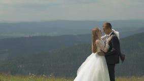 Groom with bride having fun on a mountain hills. Wedding couple hugging stock footage Groom with bride having fun on a mountain hills. Wedding couple hugging stock footage