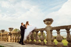 Groom holds bride& x27;s hand while she sits on ol stone handrails stock image Groom holds bride& x27;s hand while she sits on ol stone handrails stock image