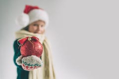 Grote rode Kerstmisbal in handen bij het meisje Het kind is gekleed in sweater, Kerstmishoed en het schot van de sjaalstudio Stock Afbeelding Grote rode Kerstmisbal in handen bij het meisje Het kind is gekleed in sweater, Kerstmishoed en het schot van de sjaalstudio Stock Afbeelding