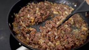 Ground beef fried with onions in a black pan