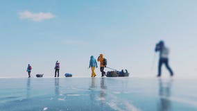 一群人在冰面上移动的地面镜头。装备齐全的探险队。清楚的蓝色换乘背景股票录像