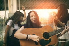 Group of asian teenager standing outdoor plying spanish guitar and dancing with happiness emotion stock photo Group of asian teenager standing outdoor plying spanish guitar and dancing with happiness emotion stock photo