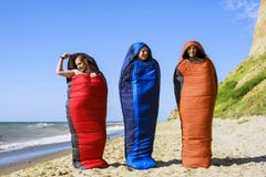 Group of cheering hikers jumping in a sleeping bags on the seaside stock photography Group of cheering hikers jumping in a sleeping bags on the seaside stock photography